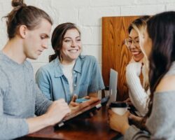 Fire personer samles rundt et bord med kaffe og samtale